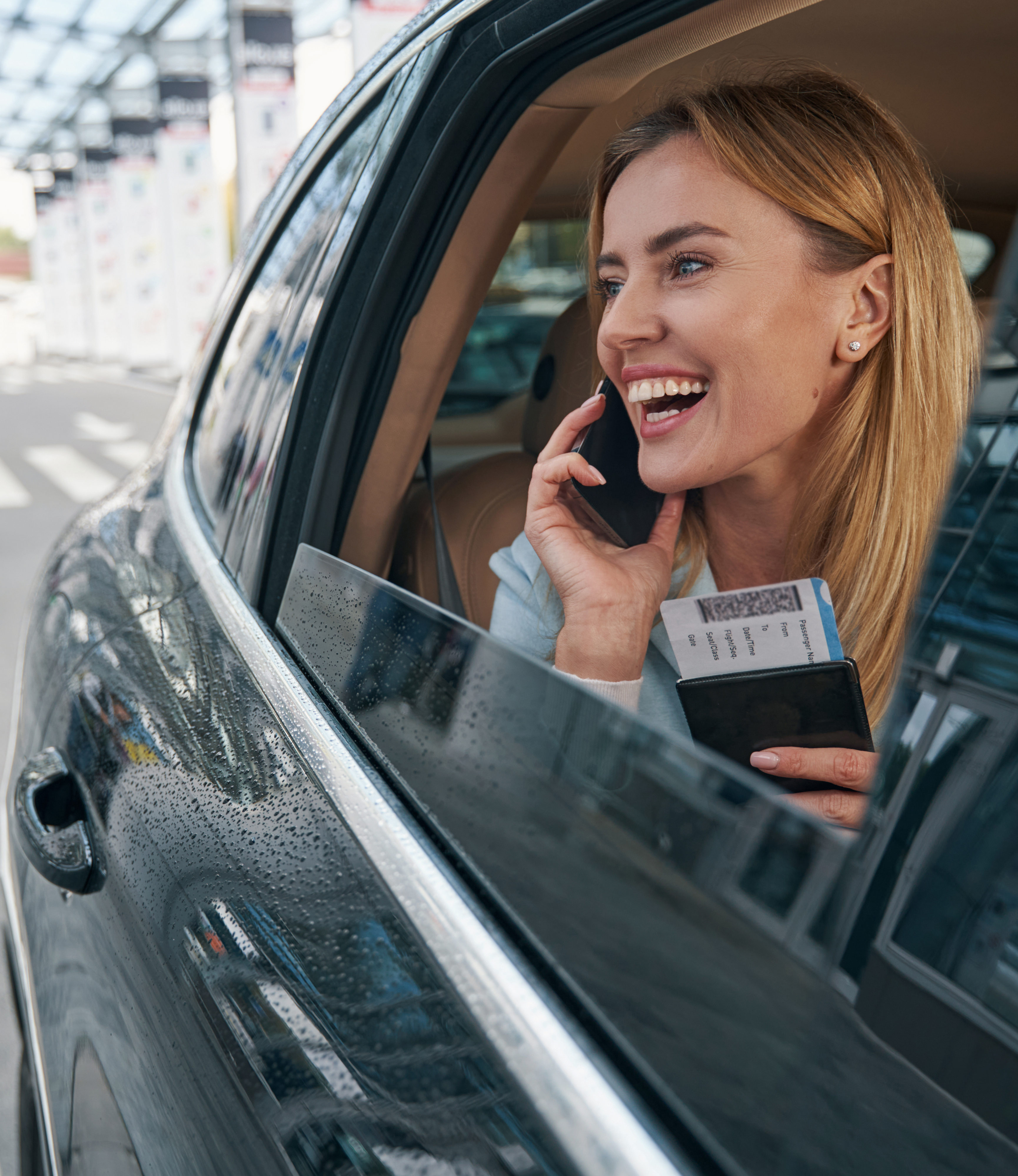 Cheerful passenger seated in car talking on smartphone